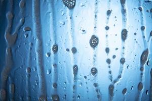 water druppels met schuim Aan glas Aan een blauw achtergrond. foto