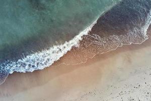 kustlijn met blauw zee golven en zand strand, top visie foto