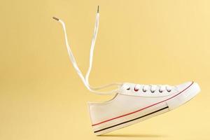 wit gewoontjes sportschoenen Aan geel achtergrond, creatief minimalisme foto