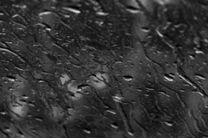 water druppels Aan glas structuur abstract zwart donker achtergrond, selectief focus foto