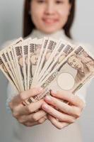 vrouw hand- Holding Japans yen bankbiljet stapel. duizend yen geld. Japan contant geld, belasting, recessie economie, inflatie, investering, financiën en boodschappen doen betaling concepten foto