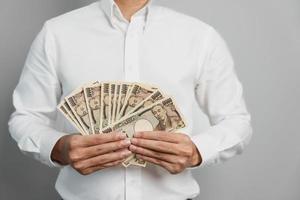 Mens hand- Holding Japans yen bankbiljet stapel. duizend yen geld. Japan contant geld, belasting, recessie economie, inflatie, investering, financiën en boodschappen doen betaling concepten foto