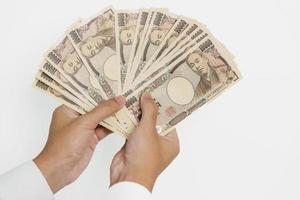 Mens hand- Holding Japans yen bankbiljet stapel. duizend yen geld. Japan contant geld, belasting, recessie economie, inflatie, investering, financiën en boodschappen doen betaling concepten foto