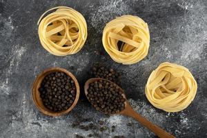 droge tagliatelle nesten en gemalen rode peper op een marmeren achtergrond foto