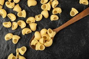 een houten lepel ongekookte conchiglie macaroni foto