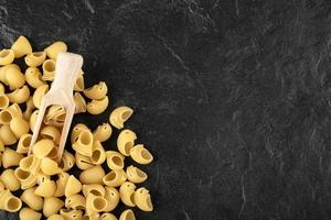 een houten lepel ongekookte conchiglie macaroni foto