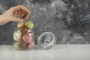 vrouw hand nemen van een donut uit een glazen pot foto