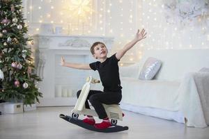 jongen Aan een speelgoed- brancard in de Kerstmis kamer. gelukkig kind Bij Kerstmis Bij huis foto