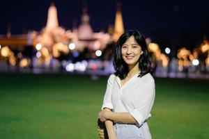 portret jong mooi Aziatisch vrouw glimlachen terwijl reizen Bij tempel van de smaragd Boeddha of wat phra kaew in nacht visie punt, Bangkok, Thailand. foto