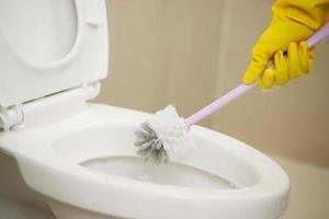 huisvrouwen gebruik borstels naar schoon de badkamer en nemen zorg van sanitair waren. foto