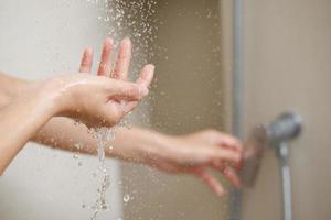 een vrouw toepassingen hand- naar meten de water temperatuur van een water kachel voordat nemen een douche foto
