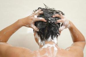 een Mens is het wassen zijn haar- met shampoo foto