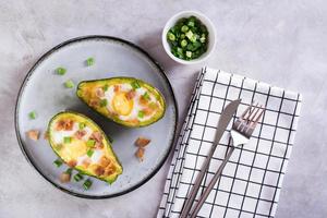 gebakken avocado met ei, spek en bieslook Aan een bord Aan de tafel voor een keto eetpatroon top visie foto