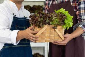 Aziatisch groenteboer met arbeider verkoop vers biologisch groen sla Aan lokaal markt foto