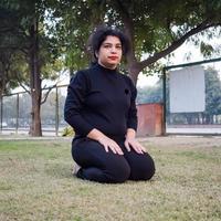 jong Indisch vrouw beoefenen yoga buitenshuis in een park. mooi meisje praktijk eenvoudig yoga houding. rust en kom tot rust, vrouw geluk. eenvoudig yoga poses buitenshuis foto