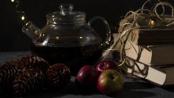 glas theepot, oud boeken, pijnboom bomen en appels. slinger lichten. nacht afbeelding. Kerstmis humeur. foto