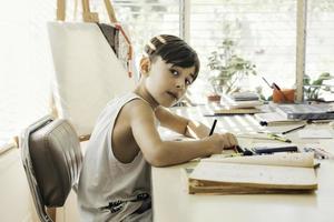 jongen zittend in zijn tekening klasse met een pen in zijn hand- tekening en kleuren. foto