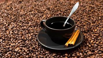 zwarte koffiemok en pijpjes kaneel op de achtergrond van koffiebonen