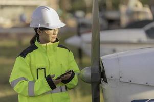 technicus die de motor van het vliegtuig repareert, vrouwelijke lucht- en ruimtevaarttechniek die vliegtuigmotoren controleert, aziatisch monteur onderhoud inspecteert vliegtuigmotor; foto