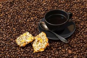 zwarte koffiemok en koekjes op de achtergrond van koffiebonen foto