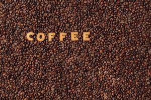 het woord koffie gemaakt van koekje letters op een donkere koffieboon achtergrond foto