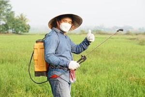 Aziatisch boer is sproeien biologisch kunstmest Bij rijstveld veld. duim omhoog. concept gebruik makend van vriendelijk Product met milieu landbouw met Nee Chemicaliën gebruik makend van. veiligheid met gebruiker en omgeving. foto