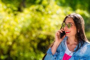 mooie, emotionele, jonge vrouw in zonnebril praten aan de telefoon foto