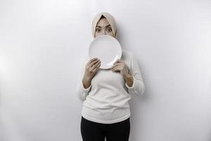 een Aziatisch moslim vrouw is vastend en hongerig en Holding een bord terwijl op zoek terzijde denken over wat naar eten foto