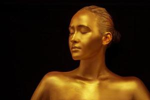 model- meisje met gouden professioneel kunst bedenken Aan een zwart achtergrond. mooi gouden metalen lichaam, lippen en huid foto