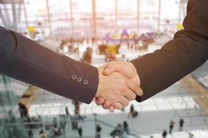 handdruk tussen twee zakenlieden in een luchthaven, bedrijfsconcept foto