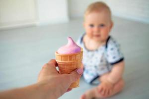 dichtbij omhoog de vrouw hand- strekt zich uit veelkleurig ijs room, Bij een achtergrond uit van focus de weinig kind foto