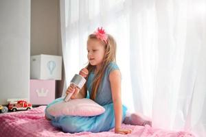 mooi weinig meisje in een prinses kostuum zingt in een karaoke microfoon. foto