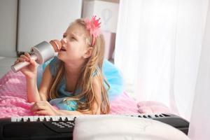 mooi weinig meisje in een prinses kostuum zingt in een karaoke microfoon. foto