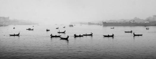 in de 's middags middag, mensen zijn kruispunt de rivier- door boot en deze jaar de mist van de winter is overspoeld in de rivier- buriganga. foto