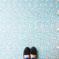 selfie van vrouw schoenen Aan blauw keramisch tegel verdieping achtergrond. foto