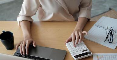 bovenaanzicht van een vrouw die werkt op een laptop en rekenmachine foto