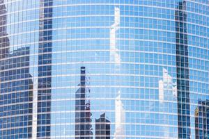 de reflectie van wolk en gebouwen in de ramen van modern kantoor gebouw foto