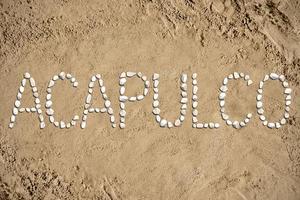 acapulco - woord gemaakt met stenen Aan zand foto