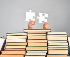 vrouw handen Holding groot wit puzzels over- een stack van boeken foto