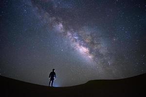 melkwegstelsel met een man die staat en kijkt naar de teerwoestijn, jaisalmer, india