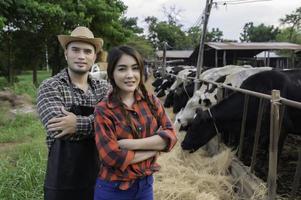 aziatische boer werkt in een landelijke melkveehouderij buiten de stad, jonge mensen met koe foto