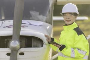 technicus die de motor van het vliegtuig repareert, vrouwelijke lucht- en ruimtevaarttechniek die vliegtuigmotoren controleert, aziatisch monteur onderhoud inspecteert vliegtuigmotor; foto