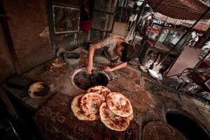 een oud verkoper verkoop gebakken naan Aan de oud straat van kashgar foto