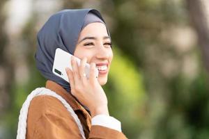 afgeleid glimlachen moslim vrouw pratend naar de mobiel foto