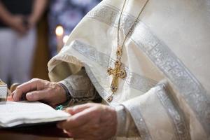 orthodox geloof. handen van de priester tegen de achtergrond van de kruis en kaarsen. foto