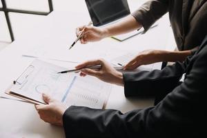 financiële analisten analyseren zakelijke financiële rapporten over een investeringsproject voor digitale tabletplanning tijdens een discussie op een bijeenkomst van bedrijven die de resultaten van hun succesvolle teamwerk laten zien. foto