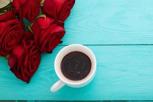 kop van koffie met croissants en koekjes en rood rozen Aan blauw houten achtergrond. kopiëren ruimte. bespotten omhoog. top visie. Valentijn moeder dag. foto