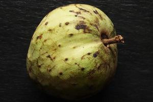 hele cherimoya fruit op leisteen achtergrond foto