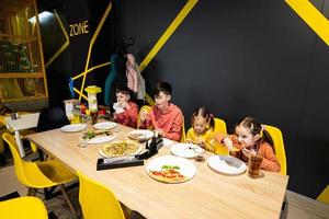 vier kinderen aan het eten Italiaans pizza in pizzeria. kinderen eten Bij cafe. foto