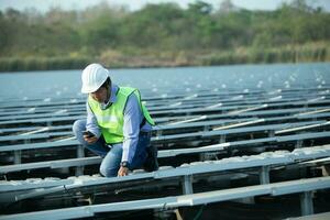 ingenieur inspecteur Holding laptop en werken in zonne- panelen macht fabriek controle fotovoltaïsche cellen en elektriciteit productie. foto